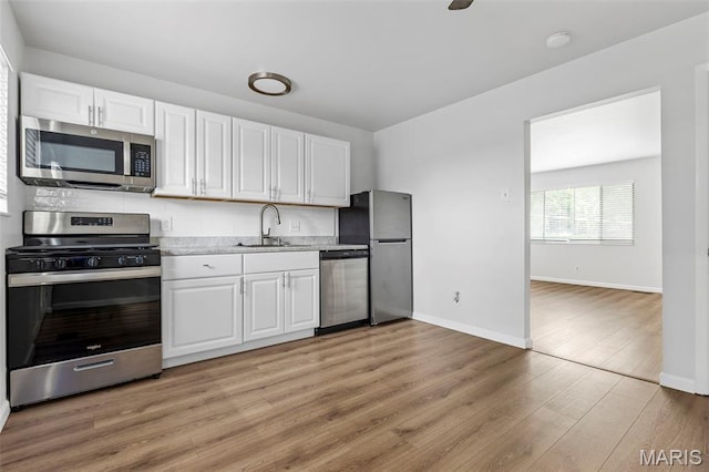 3401 Droste Rd, Saint Charles, MO 63301 - kitchen with appliances with stainless steel finishes, a sink, white cabinetry, light countertops, and light wood finished floors