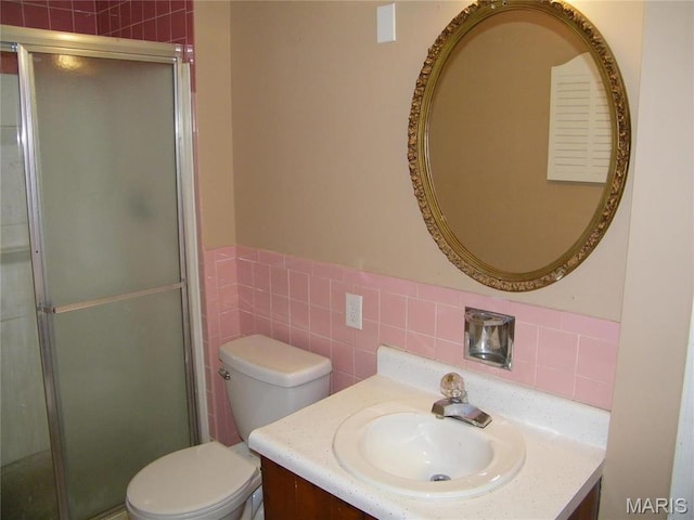 574 Coach Light Ln, Hazelwood, MO 63042 - bathroom with tile walls, a stall shower, vanity, toilet, and a wainscoted wall