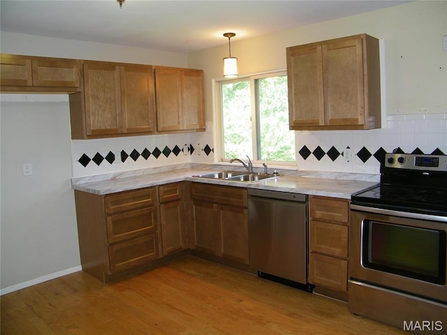 574 Coach Light Ln, Hazelwood, MO 63042 - kitchen featuring appliances with stainless steel finishes, a sink, light countertops, tasteful backsplash, and light wood-style flooring