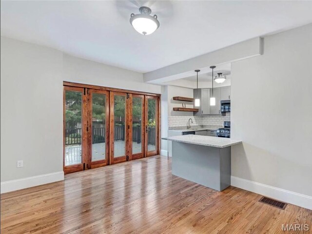 2907 S Kingshighway Blvd, Saint Louis, MO 63139 - kitchen with open shelves, french doors, a peninsula, range with gas stovetop, and baseboards