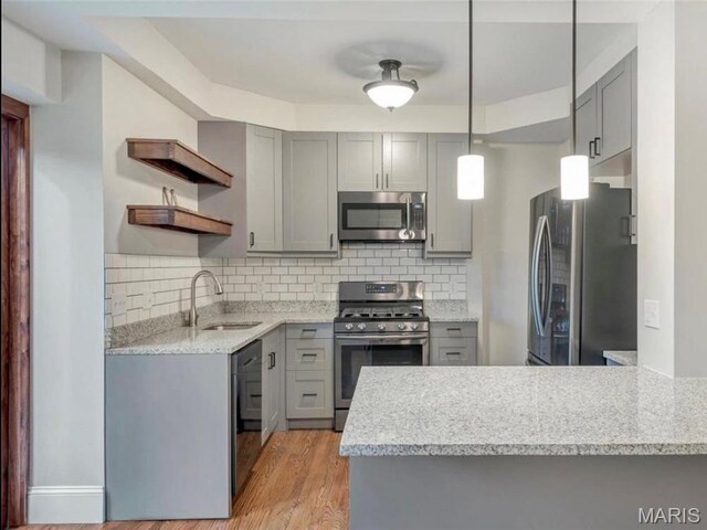 2907 S Kingshighway Blvd, Saint Louis, MO 63139 - kitchen with appliances with stainless steel finishes, open shelves, a sink, gray cabinets, and a peninsula