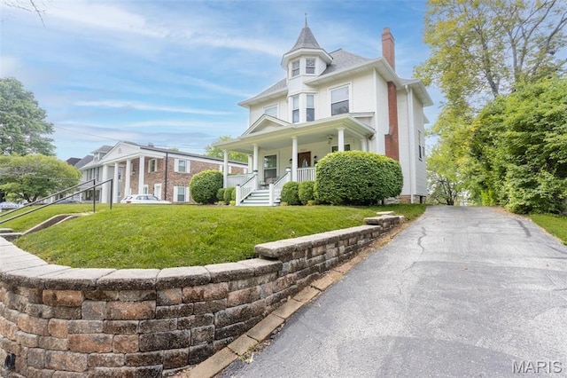 view of front of house with a chimney, a porch, and a front lawn