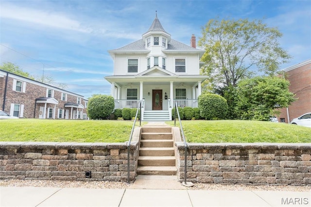 view of front of property featuring a chimney, a porch, and a front lawn
