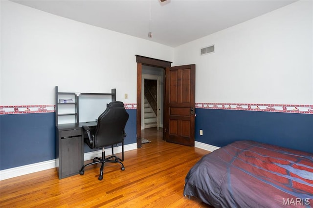 bedroom featuring wood finished floors, baseboards, and a desk