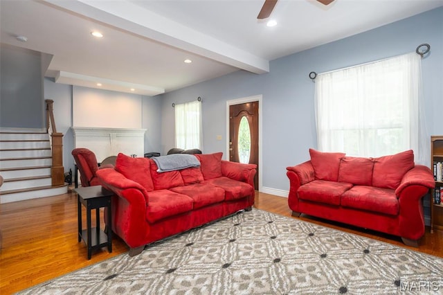 living area featuring beam ceiling, stairs, wood finished floors, recessed lighting, and ceiling fan