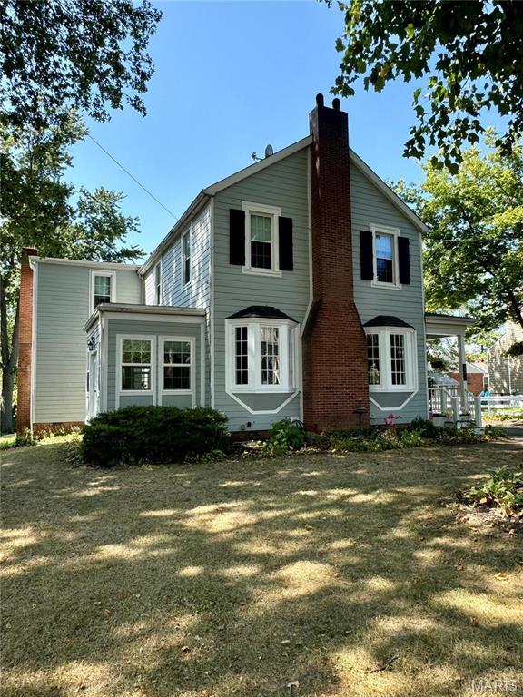 149 N Elizabeth Ave, Saint Louis, MO 63135 - back of property with a chimney, a lawn, and covered porch
