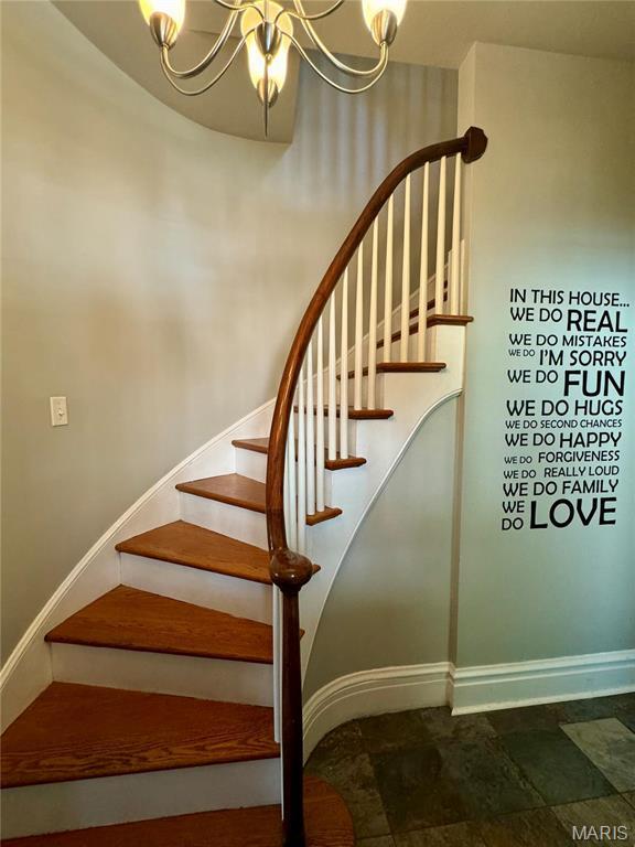 149 N Elizabeth Ave, Saint Louis, MO 63135 - staircase featuring a chandelier, baseboards, and stone finish floors