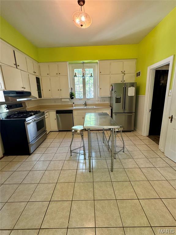 149 N Elizabeth Ave, Saint Louis, MO 63135 - kitchen featuring appliances with stainless steel finishes, under cabinet range hood, a sink, light tile patterned flooring, and white cabinets