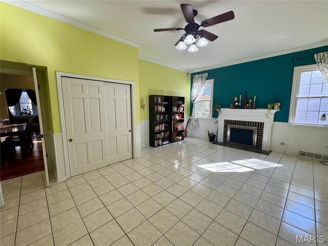 149 N Elizabeth Ave, Saint Louis, MO 63135 - living area featuring light tile patterned floors, ceiling fan, a brick fireplace, ornamental molding, and a wainscoted wall