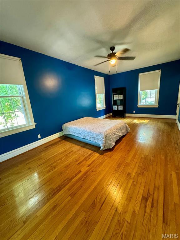 149 N Elizabeth Ave, Saint Louis, MO 63135 - unfurnished bedroom featuring wood-type flooring, baseboards, and ceiling fan