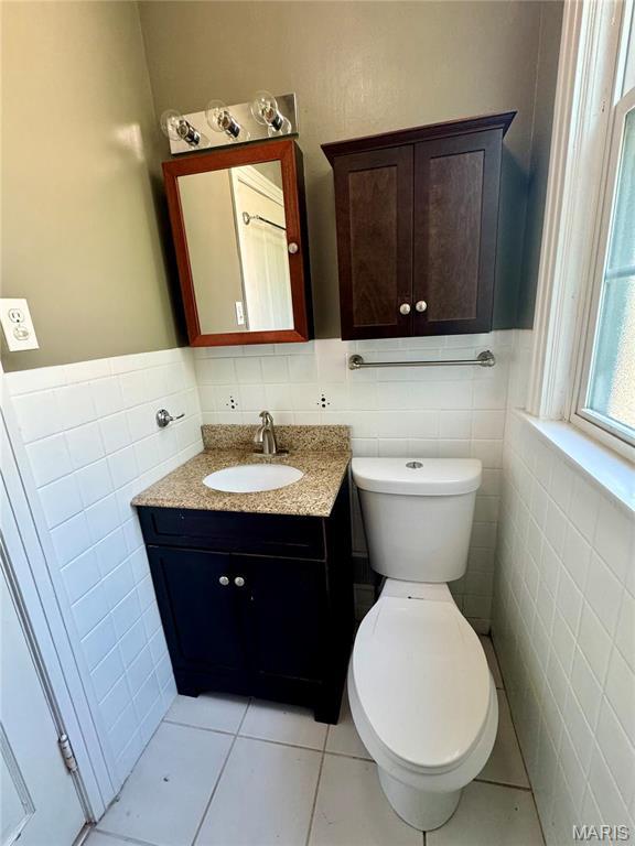 149 N Elizabeth Ave, Saint Louis, MO 63135 - bathroom featuring tile walls, vanity, tile patterned flooring, toilet, and a wainscoted wall