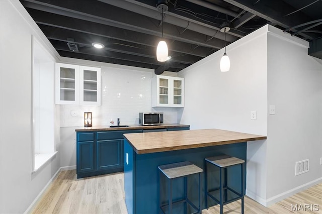 2032 Tiber St, Saint Charles, MO 63301 - kitchen featuring butcher block counters, blue cabinets, stainless steel microwave, light wood finished floors, and a breakfast bar area