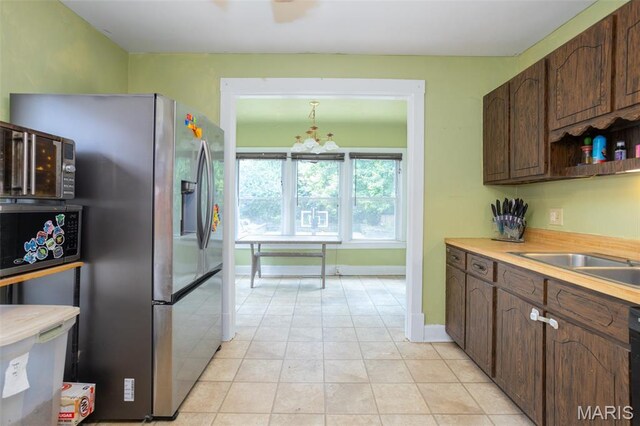 7434 Gayola Pl, Saint Louis, MO 63143 - kitchen with a chandelier, stainless steel refrigerator with ice dispenser, dark brown cabinetry, light countertops, and baseboards