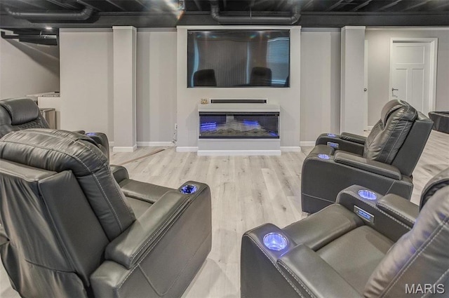 living area with wood finished floors, a glass covered fireplace, and baseboards