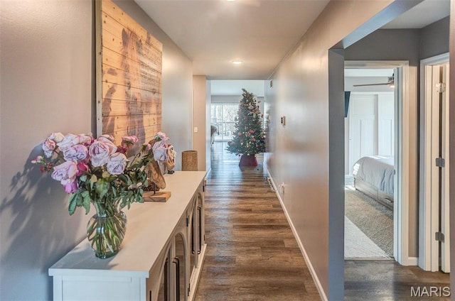 hallway featuring dark wood finished floors and baseboards