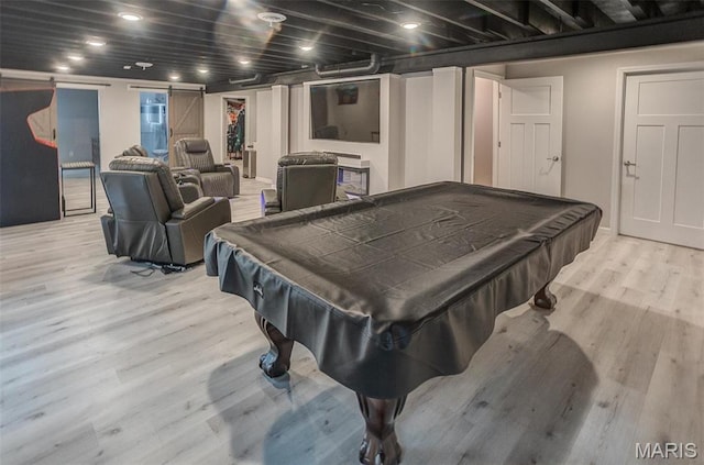 game room with light wood-style floors, a barn door, and billiards table