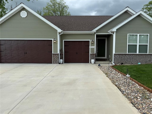 ranch-style house with brick siding, a garage, concrete driveway, and a shingled roof