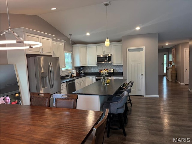 kitchen featuring stainless steel appliances, dark countertops, a sink, white cabinets, and decorative backsplash
