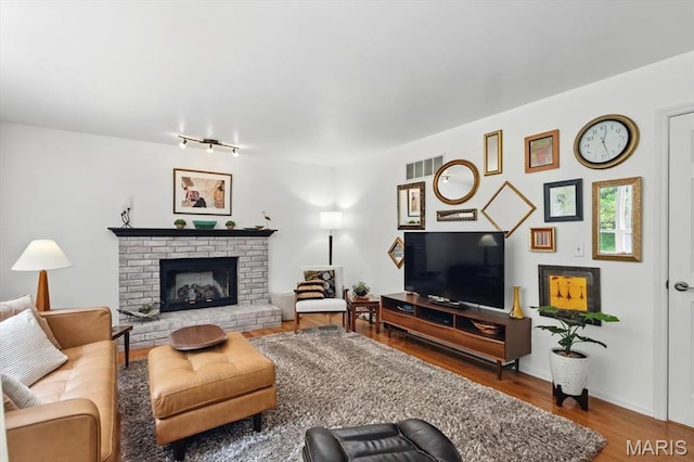17282 Hilltop Ridge Dr, Eureka, MO 63025 - living room with wood finished floors, rail lighting, and a brick fireplace