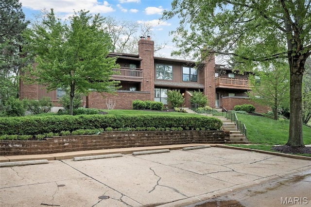 2013 Trailcrest Ln Unit 7, Saint Louis, MO 63122 - rear view of house with uncovered parking, brick siding, a yard, and a chimney
