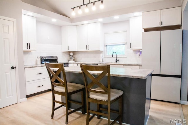 504 Leawood Dr, Swansea, IL 62226 - kitchen with freestanding refrigerator, a sink, a kitchen breakfast bar, white cabinetry, and vaulted ceiling