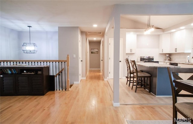 504 Leawood Dr, Swansea, IL 62226 - kitchen featuring stainless steel electric stove, a breakfast bar, white cabinets, tasteful backsplash, and light wood-type flooring