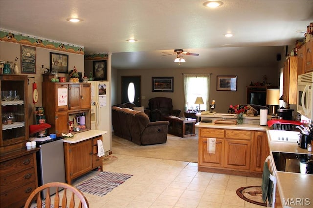 16255 Monroe Rd Unit 875, Paris, MO 65275 - kitchen featuring white microwave, a peninsula, ceiling fan, brown cabinets, and light countertops