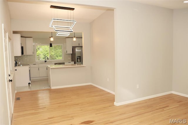 2530 N Waterford Dr, Florissant, MO 63033 - kitchen with stainless steel fridge, light wood finished floors, light countertops, white cabinets, and baseboards