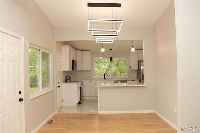 2530 N Waterford Dr, Florissant, MO 63033 - kitchen with stainless steel appliances, light countertops, light wood-style floors, tasteful backsplash, and a peninsula