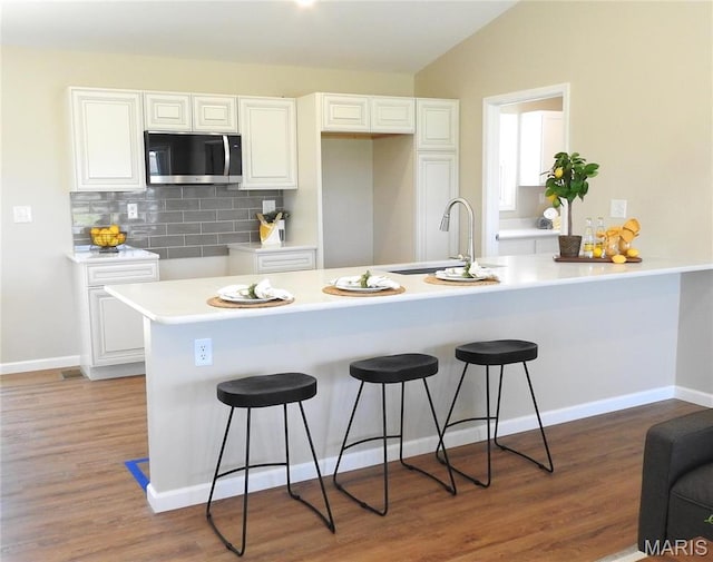 201 S Ashbrook, Bethalto, IL 62010 - kitchen featuring stainless steel microwave, a kitchen bar, white cabinetry, a sink, and vaulted ceiling