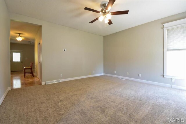 carpeted empty room featuring ceiling fan and baseboards