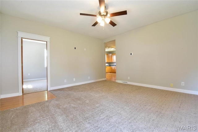 empty room with carpet floors, a ceiling fan, and baseboards