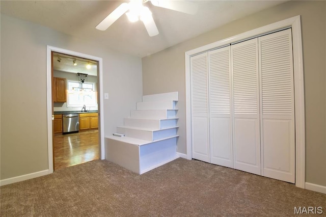 unfurnished bedroom featuring carpet floors, a closet, baseboards, and a ceiling fan