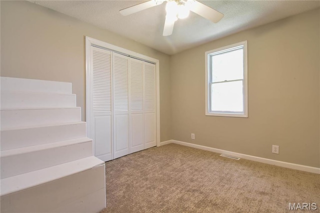 unfurnished bedroom with a closet, carpet flooring, ceiling fan, and baseboards