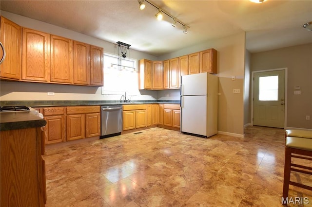 kitchen featuring freestanding refrigerator, dishwasher, healthy amount of natural light, and dark countertops