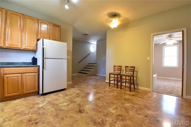 kitchen with freestanding refrigerator, dark countertops, baseboards, and a ceiling fan