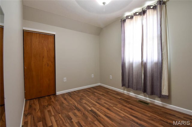 unfurnished bedroom featuring lofted ceiling, wood finished floors, and baseboards