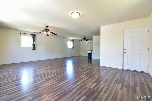 unfurnished living room featuring ceiling fan and dark wood-type flooring