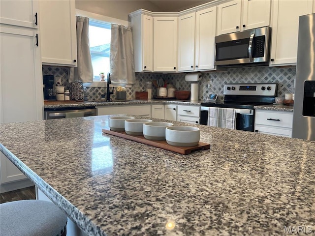210 Boardwalk Ct, Union, MO 63084 - kitchen with stainless steel appliances, white cabinetry, decorative backsplash, a sink, and dark stone countertops