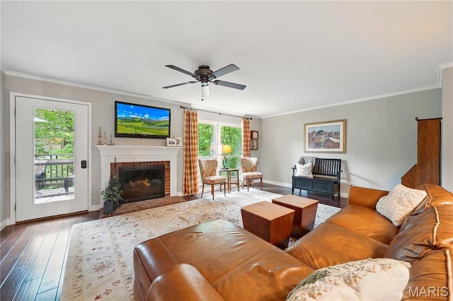 living room featuring ornamental molding, baseboards, a ceiling fan, a fireplace, and hardwood / wood-style flooring