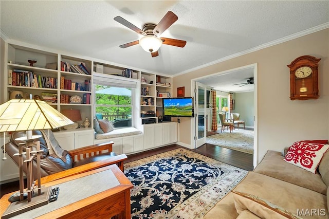 living area with ceiling fan, crown molding, wood finished floors, a textured ceiling, and built in features