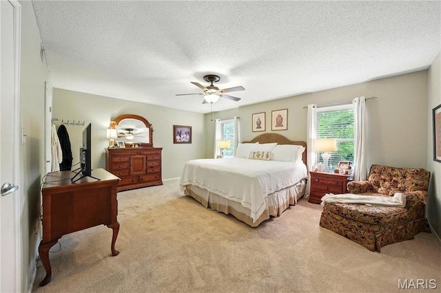 bedroom with light carpet, multiple windows, a textured ceiling, and ceiling fan