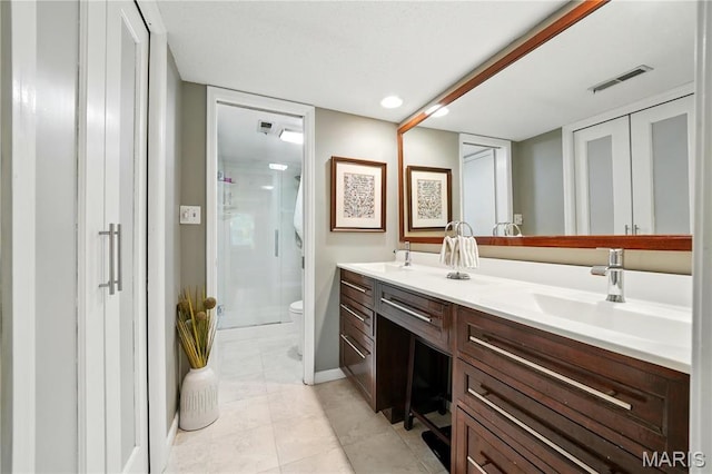 full bathroom featuring a shower stall, toilet, double vanity, and tile patterned flooring