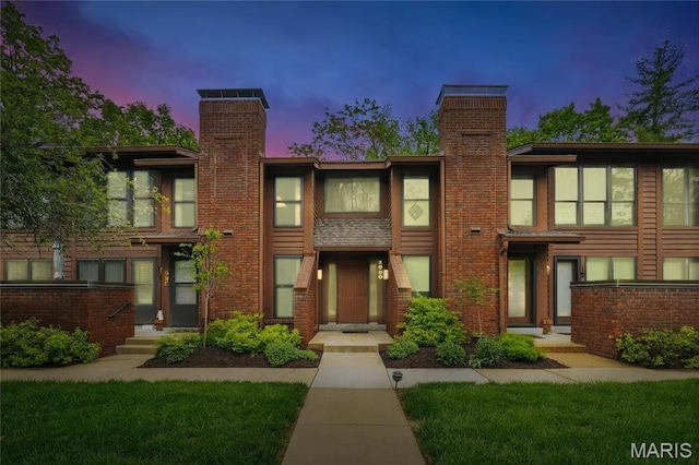 view of front of home with a chimney and brick siding