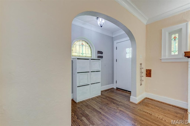 entrance foyer with arched walkways, crown molding, wood finished floors, and baseboards