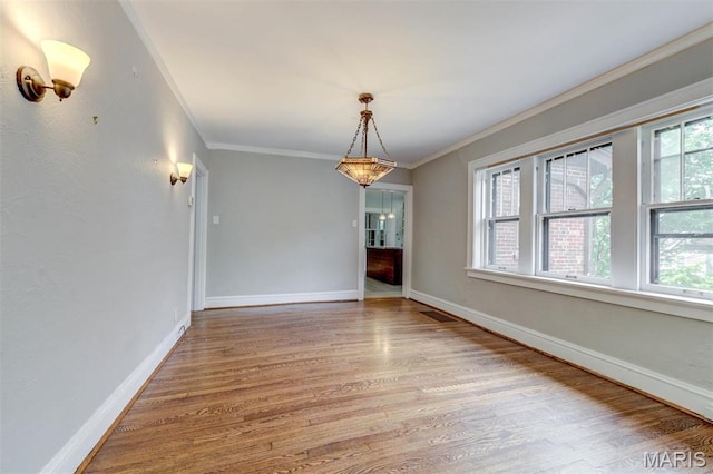 unfurnished dining area featuring ornamental molding, wood finished floors, and baseboards