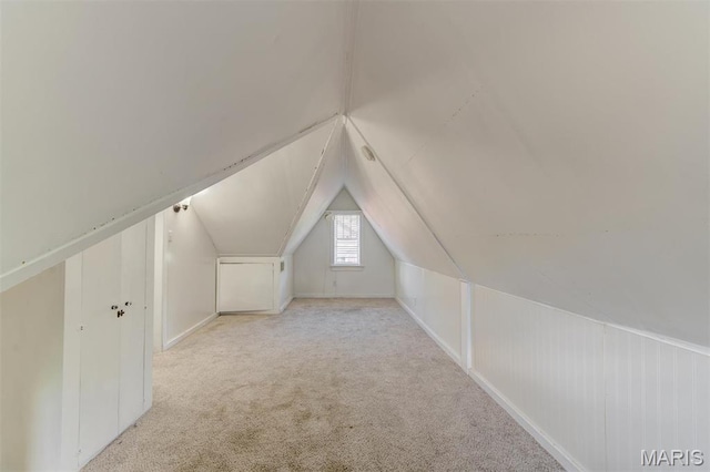 bonus room with vaulted ceiling and light carpet