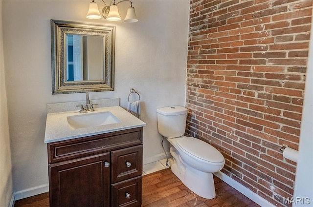339 E Ml, Millstadt, IL 62260 - bathroom with baseboards, toilet, vanity, brick wall, and wood finished floors