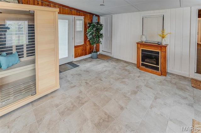 339 E Ml, Millstadt, IL 62260 - unfurnished living room featuring wood walls, baseboards, a relaxing sauna, stone finish floors, and a glass covered fireplace