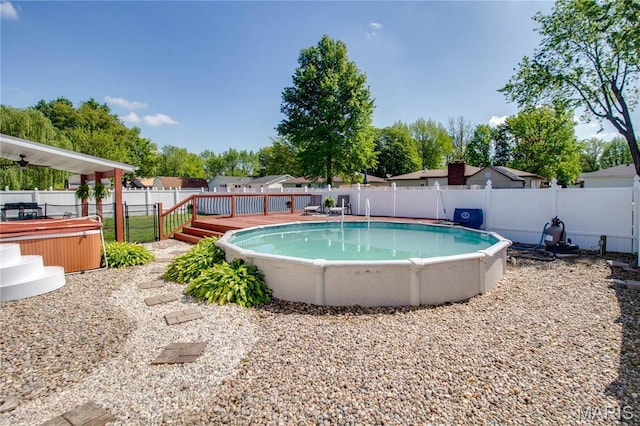view of pool featuring a wooden deck, a fenced backyard, and a hot tub